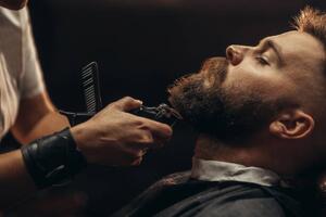 Fotografi Young bearded man getting beard haircut, zamrznutitonovi