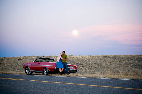 Konstfotografering man and woman next to a red convertible, Mike Kemp, (40 x 26.7 cm)